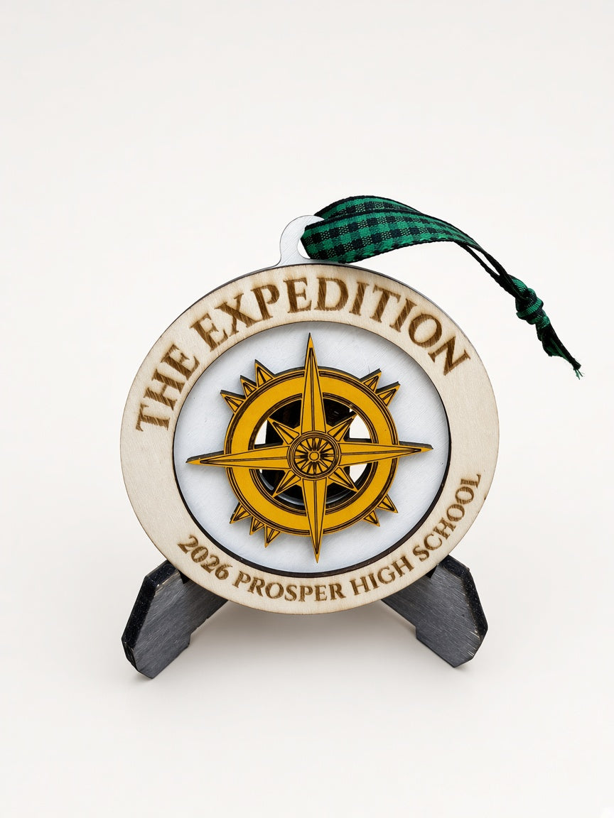 Laser-engraved wood ornament reading 'THE EXPEDITION' and '2026 PROSPER HIGH SCHOOL', displayed on a stand against a white background